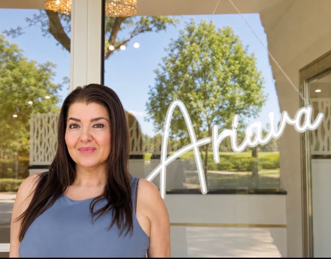 Jenna, founder of Ariava Medical Aesthetics, beside the Ariava sign